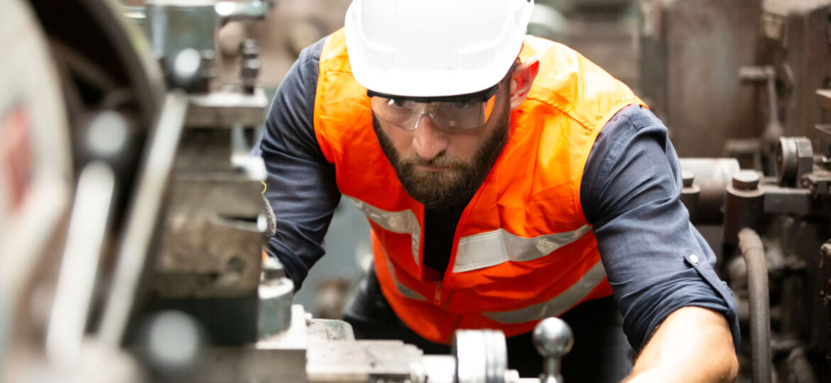 Industrial worker operating cnc turning machine in metal machining industry