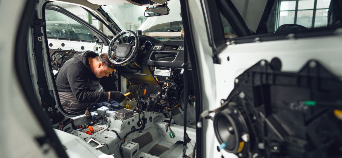 Car service worker installing noise insulation soundproofing in the car
